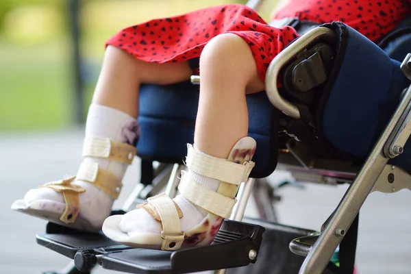 stock image Disabled girl sitting in wheelchair. On her legs orthosis. Close up photo. Child cerebral palsy. Disability. Inclusion. Family with disabled kid.