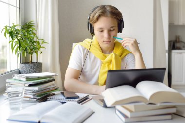Ergen çocuk evde ders çalışıyor. Çevrimiçi eğitim ve çocuklar için uzaktan öğrenme. Okullu çocuk fizik ödevini aletlerle yapıyor. Lise öğrencileri için İnternet 'te ders ve dersler