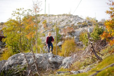 Kırmızı tişörtlü çocuk, güneşli bir günde dağ vadisinde yürüyüş yaparken doğayı keşfediyor ve eğleniyor. Enerjik çocuklar için aktif bir eğlence. Çocuklu aileler için yaz tatili
