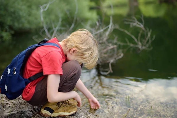 赤いシャツの前の少年は 山の谷のハイキング中に湖で自然を探索し 水で遊んでいます 精力的な子供のためのアクティブなレジャー 子供のためのサマーキャンプ屋外レクリエーション — ストック写真