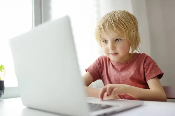 学校の少年は自宅でノートパソコンで勉強するためにコンピュータアプリを使用します 子供やガジェット 現代の技術を使用してソーシャルネットやメッセンジャーで子供たちのコミュニケーション 子供のためのオンライン教育と距離学習 — ストック写真