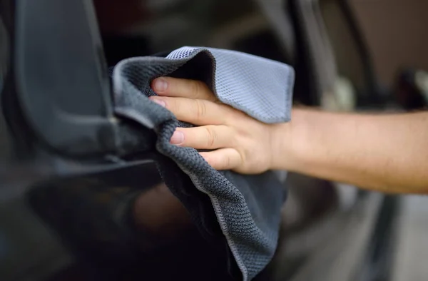 大人の男は車をぼろきれできれいにする 運転手はマイクロファイバーの洗濯布を使って車のガラスを洗う 父は自然への家族旅行のために車を準備します — ストック写真