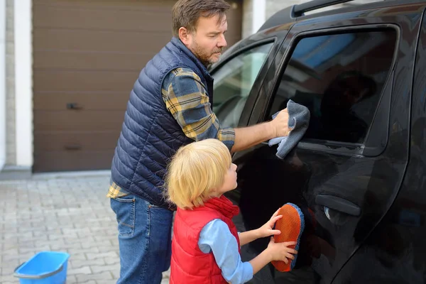 未就学児は父親が家族の車を洗うのを手伝っている パパの助けがいる 子供のいる家族は裏庭で一緒に時間を過ごす — ストック写真