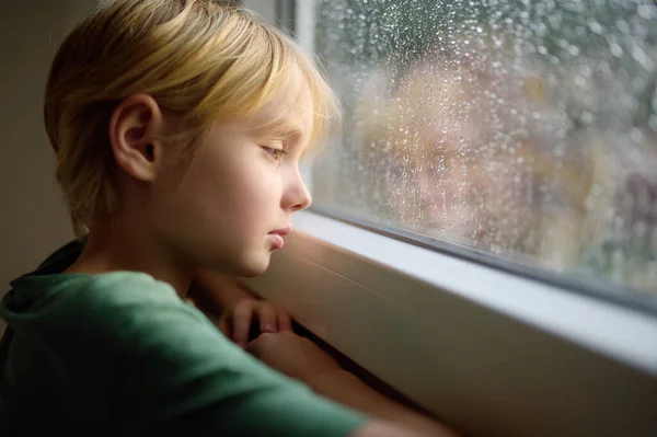 窓の前に立っている悲しい十代の少年の肖像画 外で雨を見ている子供 心的外傷後障害 悲しみの宿泊施設 損失を経験する 恐怖だ うつ病だ ストレスだ 動揺した子供 — ストック写真