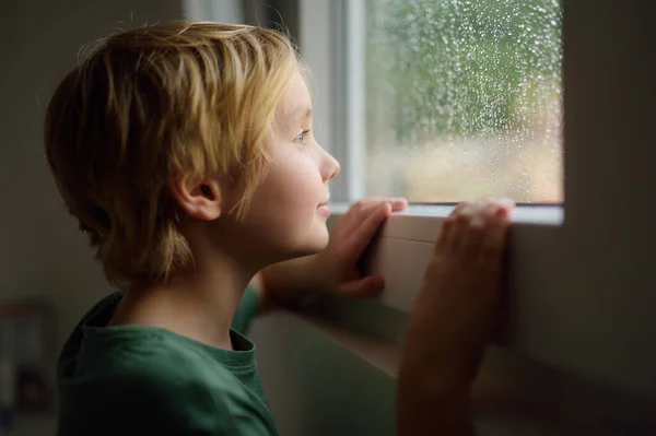 窓の前に立っている少年の肖像画 外で雨を見ている子供 信仰と希望の概念 — ストック写真