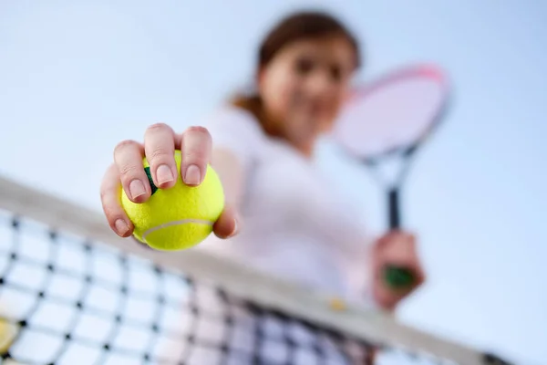 stock image Young female tennis player with tennis ball and racket preparing to serve. Girl on tennis court. Focus on ball.