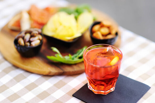 Italian aperitives/aperitif: glass of cocktail (sparkling wine with Aperol) and appetizer platter on the table. Traditional italian cuisine.