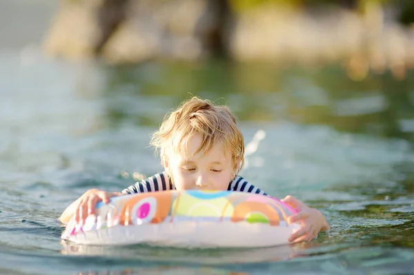 夏天阳光灿烂的日子 小男孩带着五彩缤纷的浮环在海里游泳 可爱的孩子在清澈的水中玩耍 家庭和孩子们在暑假期间度假 海上休息和放松 — 图库照片