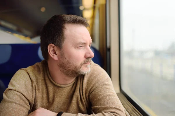 中年男子望着窗外的火车 在欧洲高速特快列车旅行中的乘客 — 图库照片