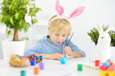 Tatlı çocuk Paskalya tatili için yumurta boyuyor. Tatile hazırlanmak çocuklar için bir eğlencedir. Küçük çocuk Paskalyayı evde kutluyor..