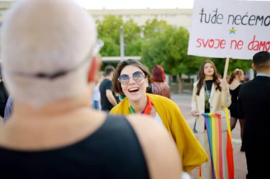 Podgorica, Karadağ - 8 Ekim 2022: Karadağ 'ın Podgorica kentinde düzenlenen On Onur Yürüyüşü sırasında halk sütununa bakış. Şehir caddesinde gökkuşağı bayrağı ve pankartlarla kalabalık var. Eşitlik için mücadele