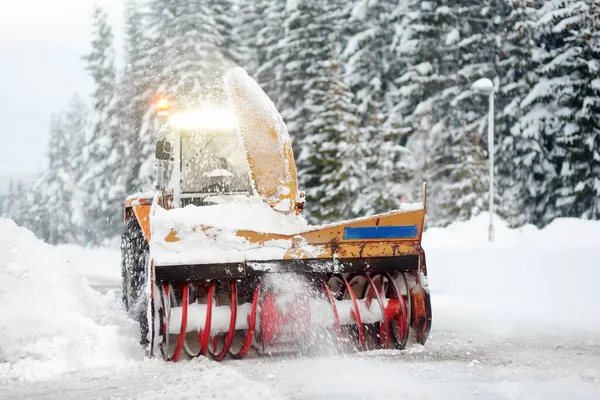 stock image A snowplow truck clearing a snow-covered road in the European Alps while a snowstorm. Drifts and snow drifts during a snowfall. Winter problems on highways