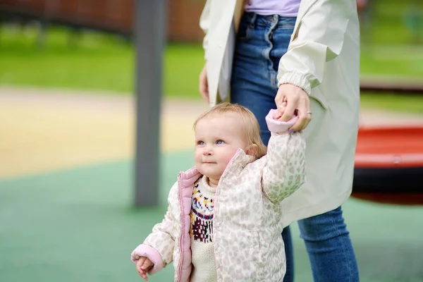 可爱的蹒跚学步的小女孩在户外操场上玩得很开心 年轻的母亲正在教她的小女儿走路 宝宝的第一步 为有小孩的家庭步行 母性快乐 — 图库照片