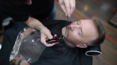 Berber ustası, kuaförde sakallı yakışıklı bir adamı tıraş ediyor. Berber dükkanında sakal ve bıyık modelliği yapan bir kuaför. Profesyonel stilistin hizmetleri. Erkekler için moda saç bakımı