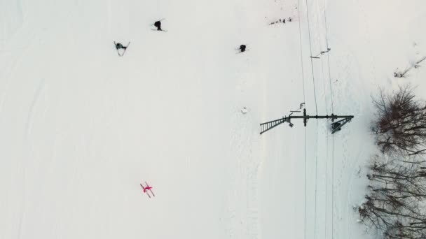 スキー場のドローンから珍しい景色 人々は斜面の上にドラッグリフトでスキーし そこからスライドします 雪の降る冬の日のためのアクティブなエンターテイメント — ストック動画