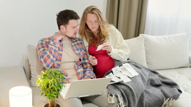 一对夫妇在笔记本电脑上把从收据到财务应用程序的费用入账 家庭正在期待一个孩子 孕妇在网上购买商品或服务时与丈夫讨论预算 家庭资金 — 图库视频影像