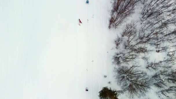 从滑雪场无人驾驶飞机上看到的异乎寻常的景象 人们乘坐拖曳电梯滑向斜坡的顶部 然后从那里滑下来 寒冷的冬日里人们的积极娱乐活动 — 图库视频影像