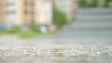 Şehrin atmosferik yağmur fırtınası videosu. Şiddetli yağmur ve su birikintileri alçak noktadan alınmış. Kaldırımda büyük damlalar kırılır. Yavaş çekim