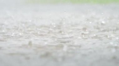Şehrin atmosferik yağmur fırtınası videosu. Şiddetli yağmur ve su birikintileri alçak noktadan alınmış. Kaldırımda büyük damlalar kırılır. Yavaş çekim