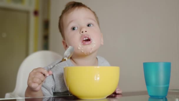 一个可爱的幼儿在厨房里吃着健康的麦片早餐 一个婴儿用勺子学习吃东西 教孩子补充营养餐的技巧 Candid家庭时刻 — 图库视频影像