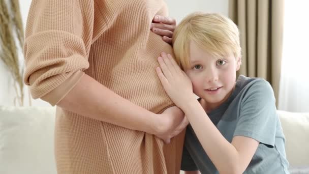 妊娠した母親の腹を抱きしめたり聞いたりする小さい少年 自宅で妊娠した母親と長男 未来の大兄さん シブリング — ストック動画