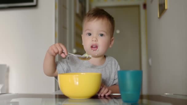 一个可爱的幼儿在厨房里吃着健康的麦片早餐 一个婴儿用勺子学习吃东西 教孩子独立吃饭的技巧 Candid家庭时刻 — 图库视频影像