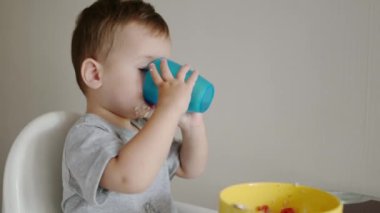 Sabahleyin mutfakta sağlıklı bir kahvaltılık gevrek yiyen tatlı bir çocuk. Bebek içkisi hala su. Çocuk beslemesi. Gizli aile anı..