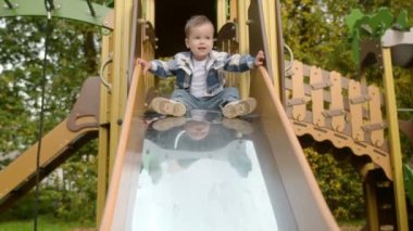Sevimli erkek bebek dışarıda oyun oynarken eğleniyor. Bebekler için aktif bir spor eğlencesi. Çocuk kayıyor. Çocuk eğlence parkı için modern ekipman.