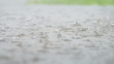 Şehrin atmosferik yağmur fırtınası videosu. Şiddetli yağmur ve su birikintileri alçak noktadan alınmış. Kaldırımda büyük damlalar kırılır. Yavaş çekim