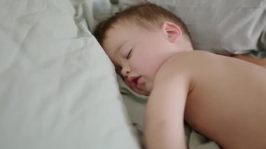  Tatlı çocuk tatlı tatlı uyuyor. Küçük çocuğun öğleden sonra uykusu. Yorgun bebek uyuyor. Günlük rutin ve uyku bebek için çok önemlidir. Çocuklar için rahat ve güzel çarşaflar..