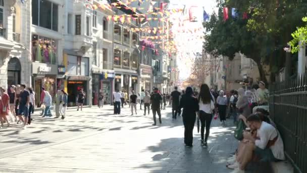 イスタンブール トルコ 2023年8月6日 晴れた夏の日にイスタンブールのBeyoglu地区で忙しいタクシムイスティクラルストリートの景色 観光客の群れは古い町で観光し 赤いレトロトラムを賞賛しています — ストック動画