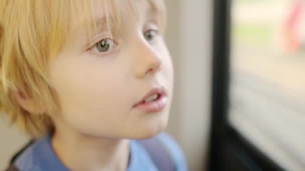 19歳の少年は地下鉄や鉄道で旅行する 子供は電車の窓の外の景色を眺めている 若い乗客は通勤列車が移動するときに手すりを持っています 都市交通システム — ストック動画