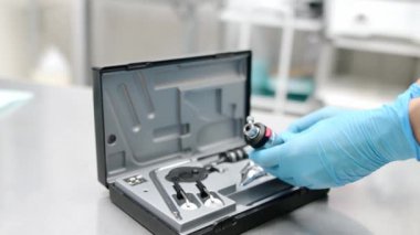 Doktor göz doktoru klinikteki gözleri incelemek için oftalmoskop hazırlıyor. Funduscopy çeşitli göz durumlarını teşhis edebilir.