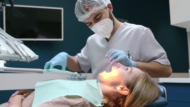 現代医療センターの歯科医と患者さん 医者は病院で若い女性の歯を治療する 矯正歯科医または義肢療法の前に麻酔をする実践者 衛生と歯が健康に — ストック動画