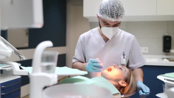 現代医療センターの歯科医と患者さん 医者は病院で若い女性の歯を治療する プラクティショナーは 矯正歯科医または義肢療法の前に患者を診察する 衛生と歯が健康に — ストック動画