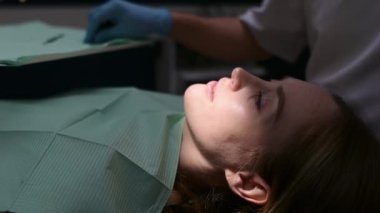 Modern tıp merkezinde dişçi ve hasta. Doktor hastanede genç bir kadının dişlerini tedavi ediyor. Pratisyen, ortodontistlerden ya da protez tedavisinden önce hastayı muayene eder. Hijyen ve diş sağlığı