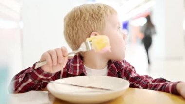 Fast food lokantasında ya da restoranda jöleli tatlı çörek yiyen tatlı sarışın çocuk. Çocuklar için sağlıksız bir yemek. Abur cubur. Küçük çocukla beslenme sorunları