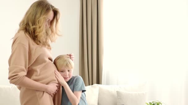Ein Schuljunge Umarmt Mama Und Hört Ihrem Schwangeren Bauch Schwangere Lizenzfreies Stock-Filmmaterial