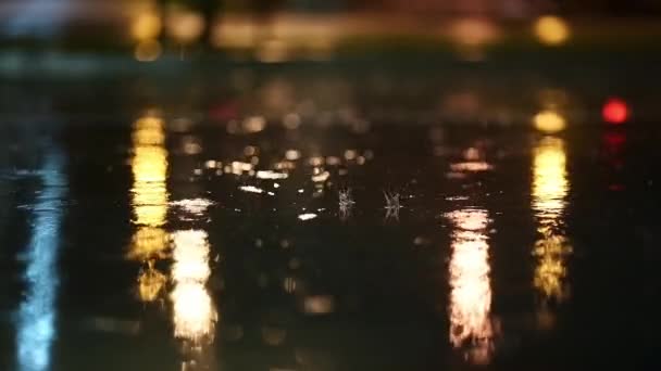 夜の街での暴風雨の大気ビデオ 低点から撮影した大雨やスプラッシュ水溜り 街灯の光の中で舗装に大きな滴が壊れます スローモーション — ストック動画