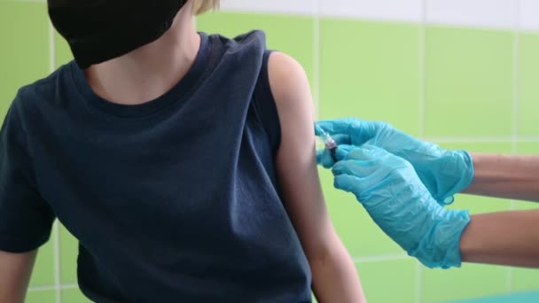 小さな少年がワクチン接種を受けている 保護マスクを着用している子供は 病気の流行または流行中にワクチンを投与されます 予定されたワクチン接種中に認識できない子供 ロイヤリティフリーストック映像