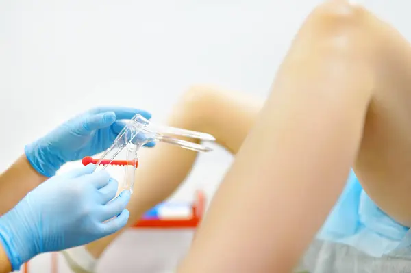 stock image Gynecologist examines a patient laying on gynecological chair using medical vaginal speculum. Doctor takes a smear from a young woman cervix. Diagnosis of diseases. Woman reproductive health.