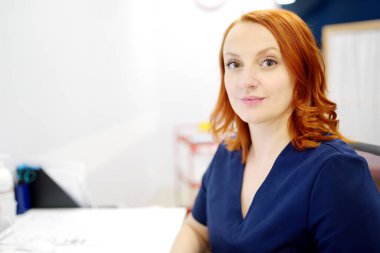 Modern bir kliniğin ofisinde kameraya bakan gülümseyen bir kadın nörologun portresi. Nöroloji doktoru işte. Güzel genç bayan kameraya bakıyor.