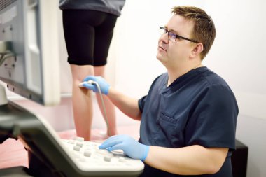 Profesyonel damar cerrahı, damar ameliyatından önce klinikte hastanın damarının ultrasonunu çekiyor. Phlebectomy. Endovasküler damar ameliyatıyla ilgili danışmanlık sırasında profesyonel doktorlar