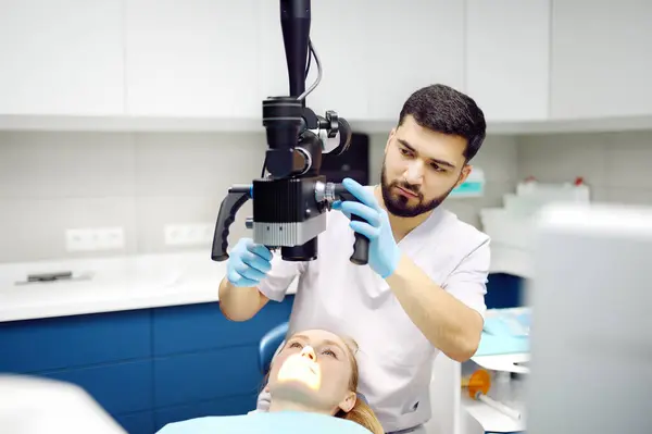 现代医疗中心的牙科医生和病人 医生用显微镜治疗年轻妇女的牙齿 在矫形外科医生或假肢治疗之前 从业者要对病人进行护理 卫生和牙齿健康 — 图库照片