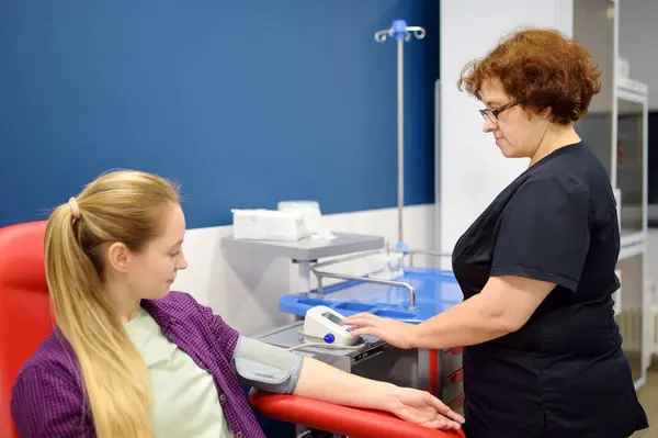 护士在抽血前测量一位年轻妇女的血压 在现代化的化验室诊所或医院检查病人的健康状况 在捐赠过程中 年轻的成年女性捐献者 — 图库照片