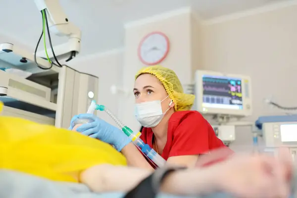 女性の麻酔科医は患者マスクに麻酔を注射する 手術中に一般的な鎮静 蘇生中に人の呼吸と換気のための酸素マスクを置くパラメディック ストックフォト