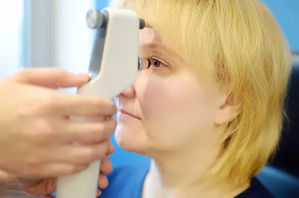 在看视光师的过程中病人 眼科医生用现代眼压仪测量住院患者的眼压 在医务室进行视力检查时对成熟妇女的特写 — 图库照片