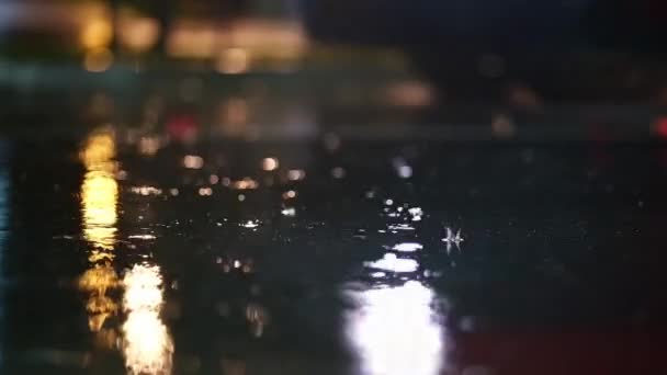 夜间城市暴雨的大气录像 大雨和飞溅的水坑从低点 街上的路灯把人行道上的大滴摔碎了 慢动作 图库视频