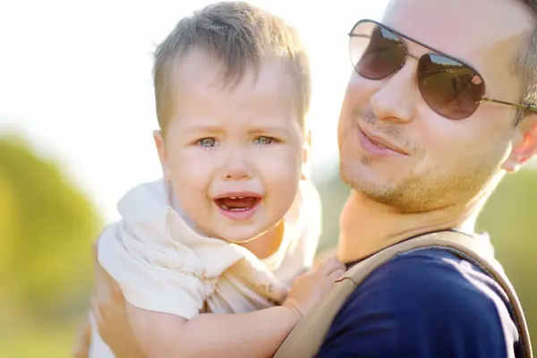 Ein Frustrierter Kleinkind Junge Weint Auf Den Armen Seines Vaters Stockfoto