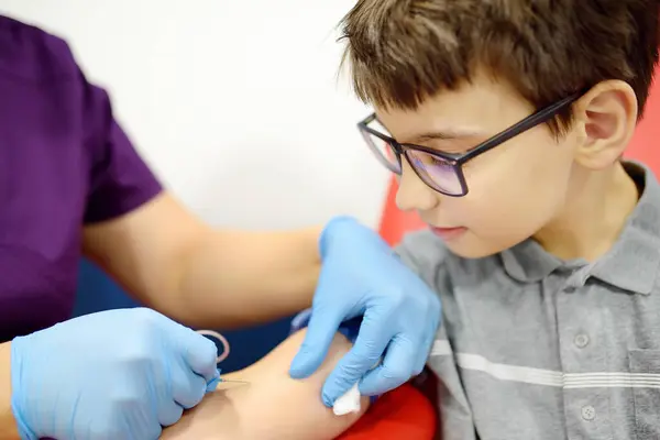 护士用蝴蝶针从小孩身上取血 在现代实验室或医院采集血液样本检查时 近距离观察男孩的手 婴儿健康检查 图库图片